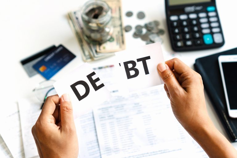 woman hands holding up a piece of paper with the word debt writt